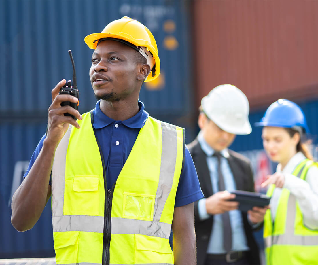 Worker using walkie talkie while newer employee is trained in background